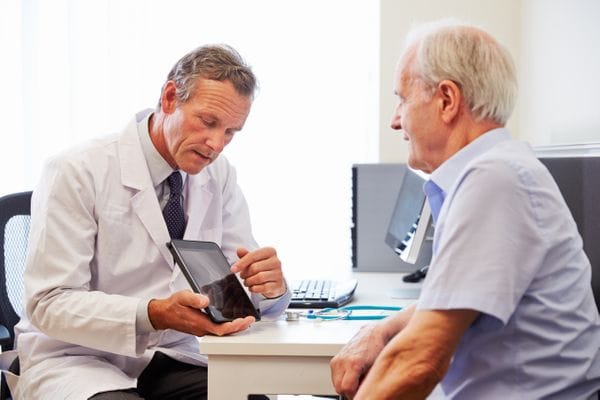 Clinician reviewing medication information on a tablet with an older patient